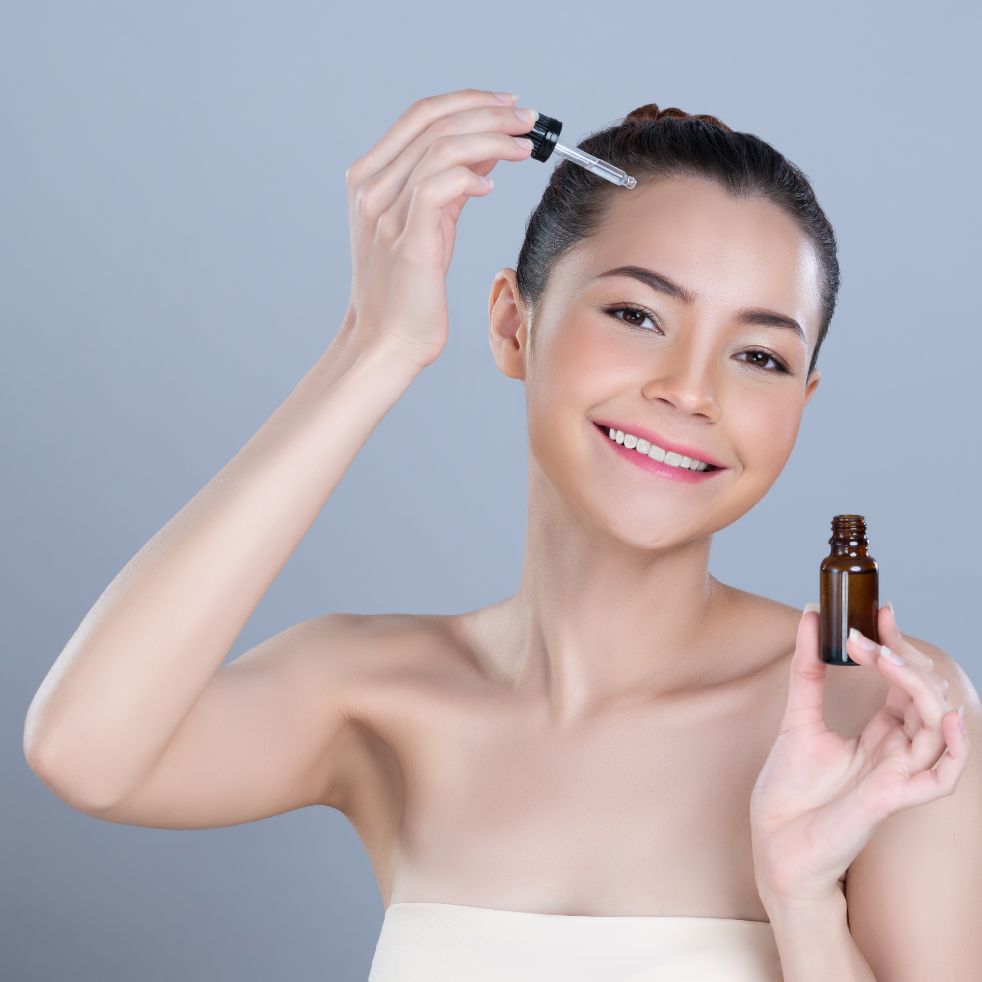 Glamorous portrait of woman applying CBD oil skincare treatment.